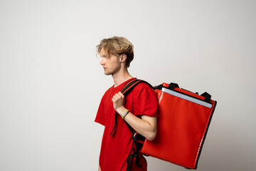 Canvas Print - Delivery man in red uniform with thermal backpack for food. Takeaway food delivery. Man delivering online food orders to customers with red thermal bag, grocery deliver.