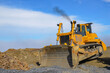 Big crawler dozer working on construction site or quarry. Mining machinery moving clay, smoothing gravel surface for new road. Earthmoving, excavations, digging on soils