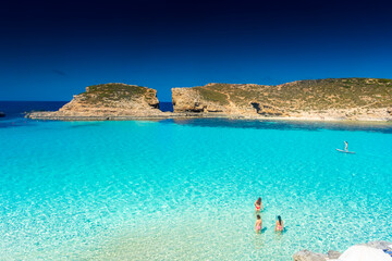 Wall Mural - Comino, Malta, 22 May 2022:  Girls enjoying the crystal clear water of the Blue Lagoon