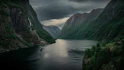 moody fjord with mountains and waterfall of aurlandsfjord at gudvangen in norway, dark clouds in the