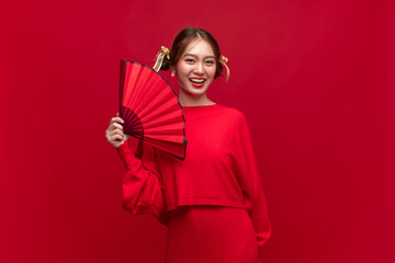 Wall Mural - Young asian woman wearing red sweater dress with Chinese folding fan on red background for Chinese new year festival