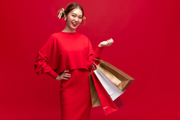 Wall Mural - Young asian woman wearing red sweater dress with shopping bags on red background for Chinese new year and Christmas festival