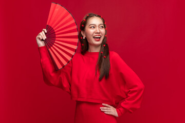 Wall Mural - Young asian woman wearing red sweater dress with Chinese folding fan on red background for Chinese new year festival