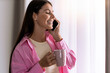 © ivanko80 - Woman drinking coffee and using phone at home