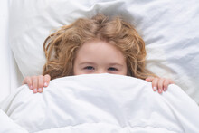 Kid Under Covers, Face Cover With Blanket. Child Wakes Up In The Morning In The Bedroom. Cute Little Boy Waking Up In Bed.