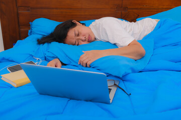 Woman in white t-shirt sleeping in blue bed sheet next to laptop computer