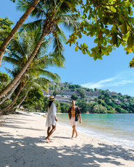 Wall Mural - A couple of men and women walking on a white tropical beach with palm trees in Phuket Thailand. 