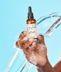 Serum, skincare and hand of a man with a water splash for an anti aging product, beauty and hair growth secret on a blue background in studio. Cosmetic, marketing and model with an oil for acne