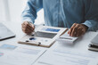 © kamiphotos - A business finance man is reviewing a company's financial documents prepared by the Finance Department for a meeting with business partners. Concept of validating the accuracy of financial numbers.