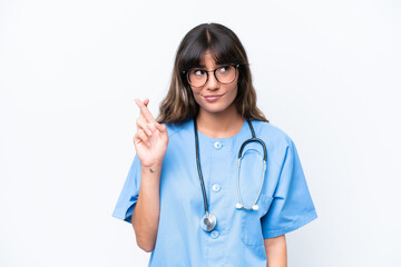 Canvas Print - Young caucasian nurse woman isolated on white background with fingers crossing and wishing the best