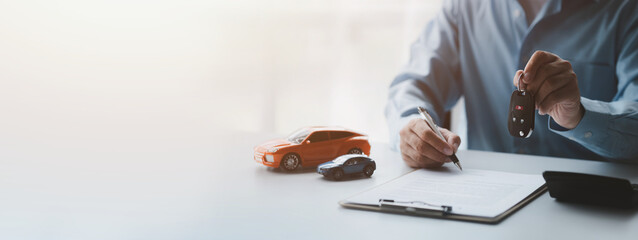 A car rental company employee pointed out the renter to sign the rental agreement after discussing the details and rental terms with the renter. Concept of car rental.