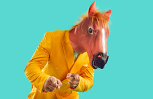 Strange Guy In Funny Disguise Invites You To Cool Party. Man Wearing Bright Yellow Suit And Masquerade Horse Mask Standing On Turquoise Studio Background, Looking At Camera And Pointing Fingers At You