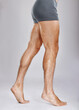 © C Davids/peopleimages.com - Man, legs or muscles on studio background for fitness check, workout training goals or studio exercise wellness. Underwear model, bodybuilder and strong athlete feet on gray backdrop for healthcare