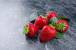 canvas print picture - Reife rote Erdbeeren aus biologischem Anbau angeboten als close-up auf einem grauen Board mit Textfreiraum