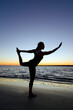 © Cavan Images - A silhouette of a woman performing yoga on the beach at sunset on Hilton Head Island, SC.