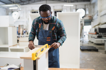 African American carpenter use Precision level to wood at wood factory	