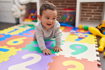 adorable hispanic baby crawling on floor at kindergarten