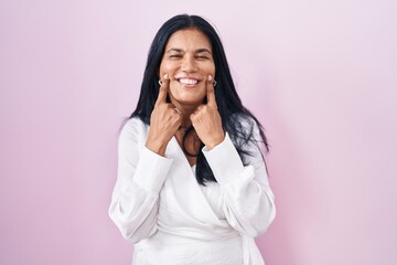 Poster - Mature hispanic woman standing over pink background smiling with open mouth, fingers pointing and forcing cheerful smile