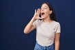 © Krakenimages.com - Young hispanic woman standing over blue background shouting and screaming loud to side with hand on mouth. communication concept.