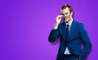 © vgstudio - Portrait of businessman in blue confident suit looking throw eye glasses, spectacles, isolated over violet purple color background. Smiling business man at studio ad concept. Copy space.