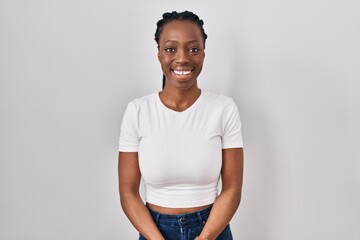 Beautiful black woman standing over isolated background with hands together and crossed fingers smiling relaxed and cheerful. success and optimistic