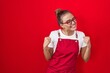 Young hispanic woman wearing waitress apron over red background very happy and excited doing winner gesture with arms raised, smiling and screaming for success. celebration concept.