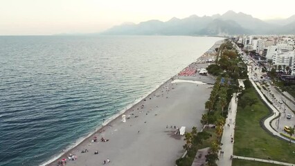 Wall Mural - Aerial view of scenic and popular Konyaalti beach in Antalya resort town. Majestic mountains with haze in background. Vacation and holiday in Turkiye
