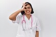 © Krakenimages.com - Young hispanic doctor woman wearing stethoscope over isolated background doing ok gesture with hand smiling, eye looking through fingers with happy face.