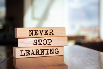 Wall Mural - Wooden blocks form the words 'Never Stop Learning' on blur background.