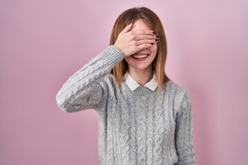 Sticker - Beautiful woman standing over pink background smiling and laughing with hand on face covering eyes for surprise. blind concept.