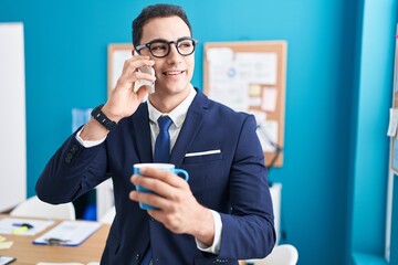 Sticker - Young hispanic man business worker talking on smartphone drinking coffee at office