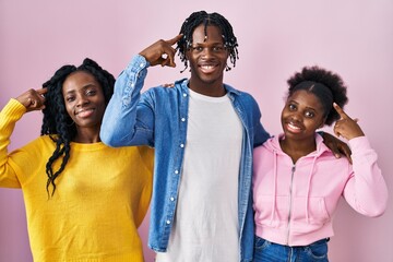 Sticker - Group of three young black people standing together over pink background smiling pointing to head with one finger, great idea or thought, good memory