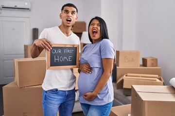 Young hispanic couple expecting a baby moving to a new home angry and mad screaming frustrated and furious, shouting with anger looking up.