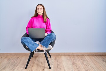 Sticker - Young hispanic girl working using computer laptop relaxed with serious expression on face. simple and natural looking at the camera.