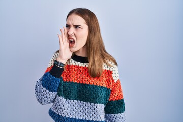 Sticker - Young hispanic girl standing over blue background shouting and screaming loud to side with hand on mouth. communication concept.