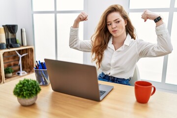 Poster - Young caucasian woman working at the office using computer laptop showing arms muscles smiling proud. fitness concept.