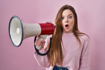 Poster - Young caucasian woman shouting through megaphone scared and amazed with open mouth for surprise, disbelief face