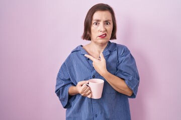 Poster - Middle age hispanic woman drinking a cup coffee pointing aside worried and nervous with forefinger, concerned and surprised expression