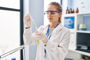 Wall Mural - Young blonde woman wearing scientist uniform working at laboratory