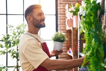 Canvas Print - Young hispanic man florist smiling confident holding plant at florist