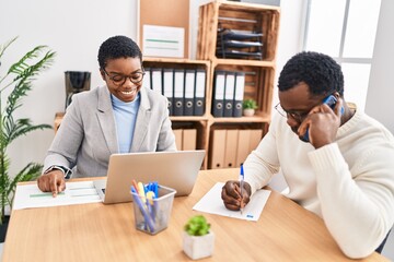 Canvas Print - Man and woman business workers using laptop and talking on the smartphone at office