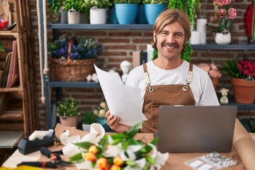 Canvas Print - Young blond man florist using laptop reading document at flower shop