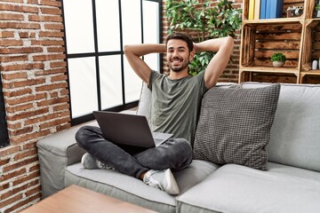 Canvas Print - Young hispanic man relaxed with hands on head using laptop at home