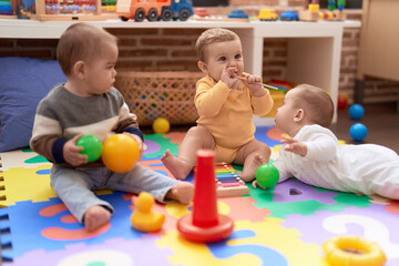  Group of toddlers playing with toys sitting on floor at kindergarten