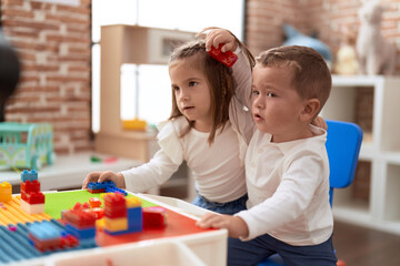 Poster - Adorable girl and boy playing with construction block pieces sitting on table at kindergarten