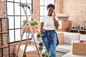 Wall Mural - African american woman smiling confident talking on the smartphone at new home