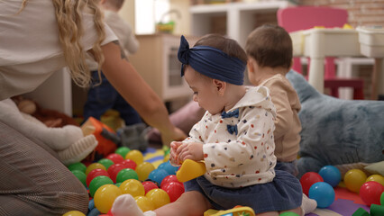 Poster - Group of toddlers playing with toys sitting on floor at kindergarten