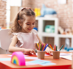 Poster - Adorable caucasian girl sitting on table drawing on paper at classroom