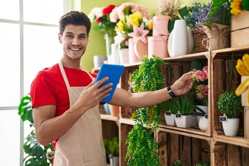 Sticker - Young hispanic man florist using touchpad touching plant of shelving at flower shop