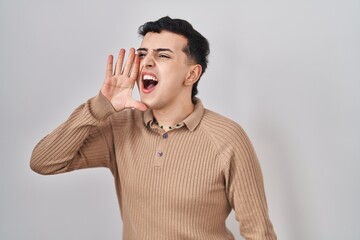 Poster - Non binary person standing over isolated background shouting and screaming loud to side with hand on mouth. communication concept.